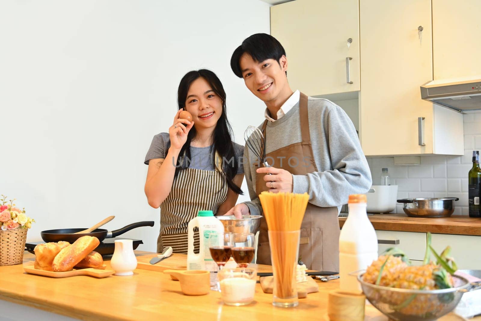 Beautiful young couple standing at worktop in the kitchen preparing and preparing breakfast together..