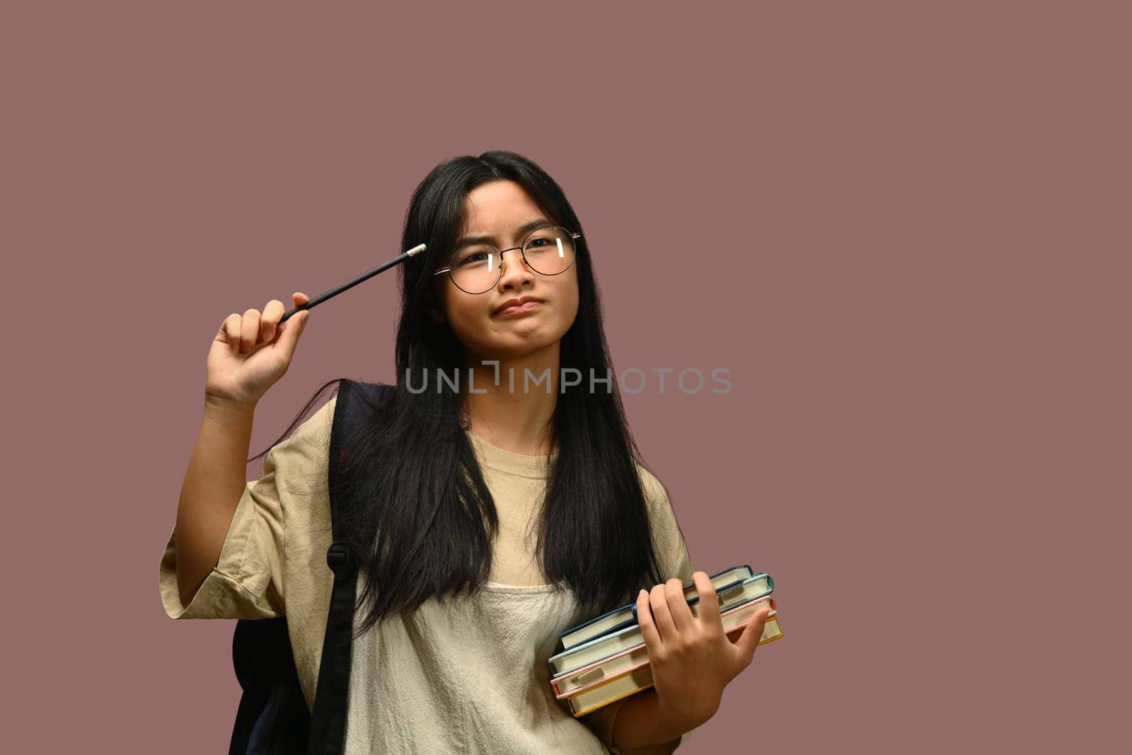 Teenager schoolgirl wearing glasses holding textbook over purple background. Educational, learning and back to school concept.