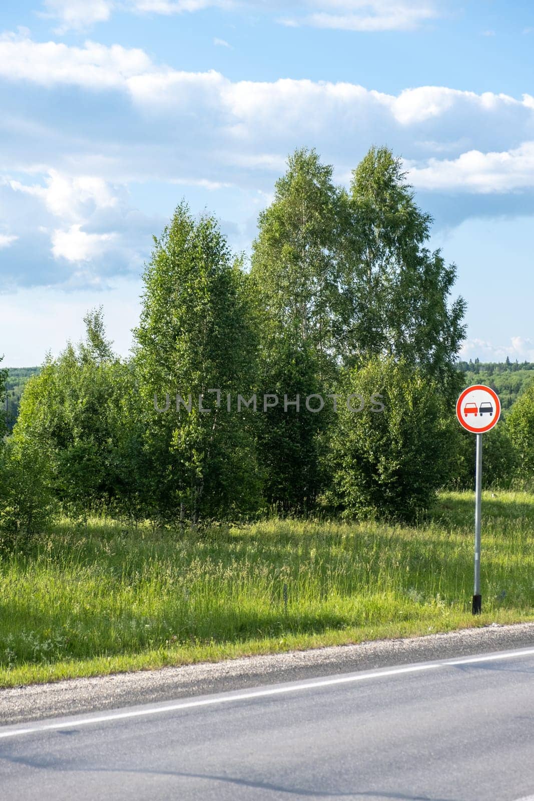 A road sign Overtaking is prohibited on a suburban highway through by AnatoliiFoto