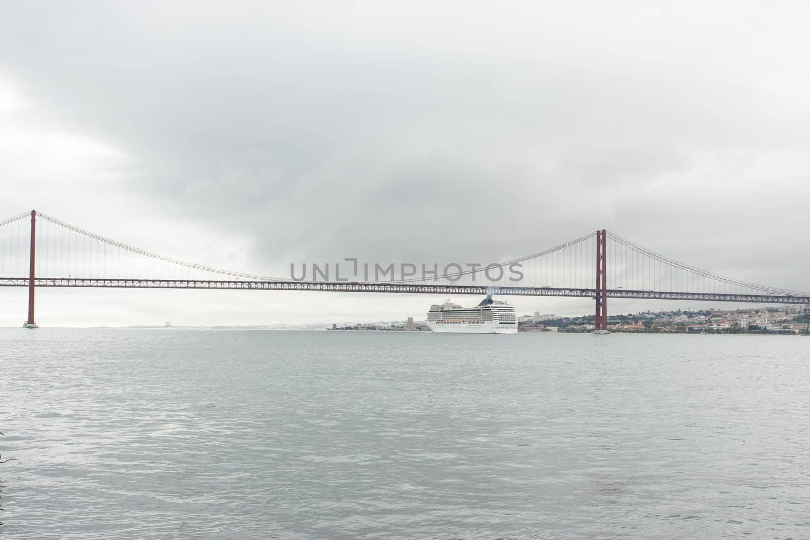 A cruise ship passes along the river under the bridge in cloudy weather. Mid shot