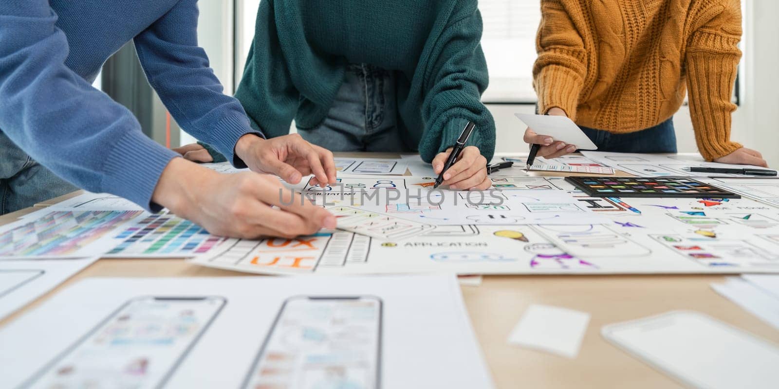 UX developer and ui designer brainstorm about mobile app interface wireframe design with customer breif and color code at office.