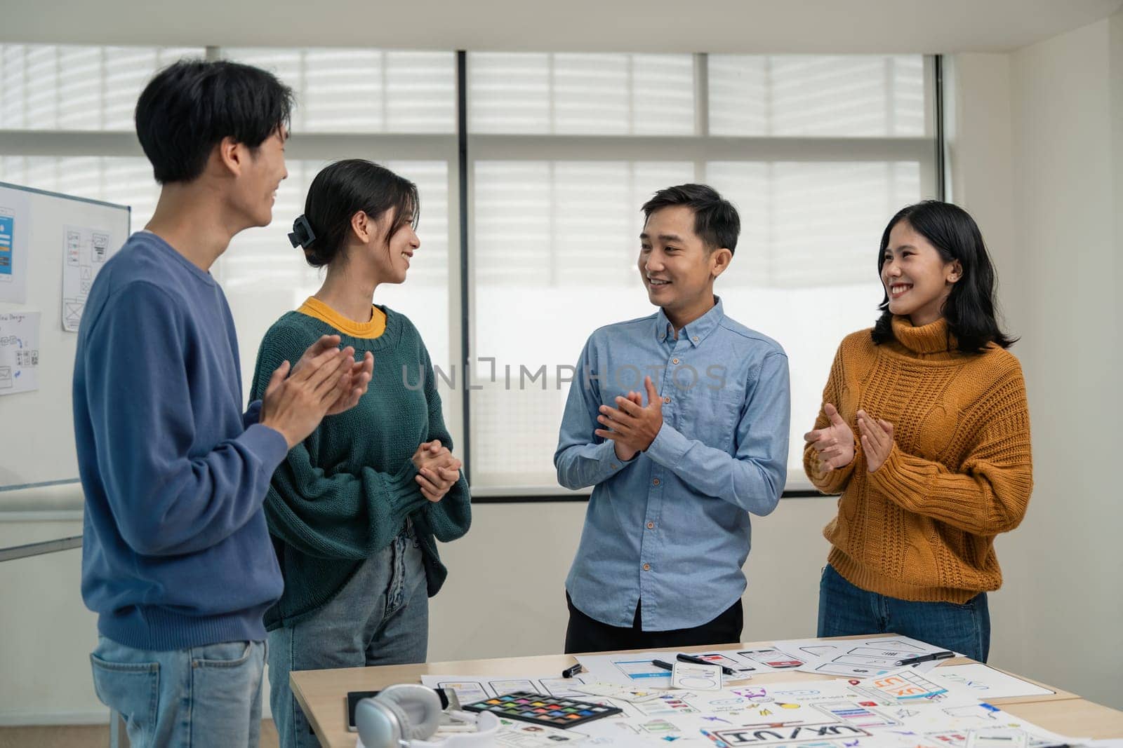 Asia team creative in smart casual wear discussing phone application design celebrate giving five after dealing feeling happy in office. Coworker teamwork concept.