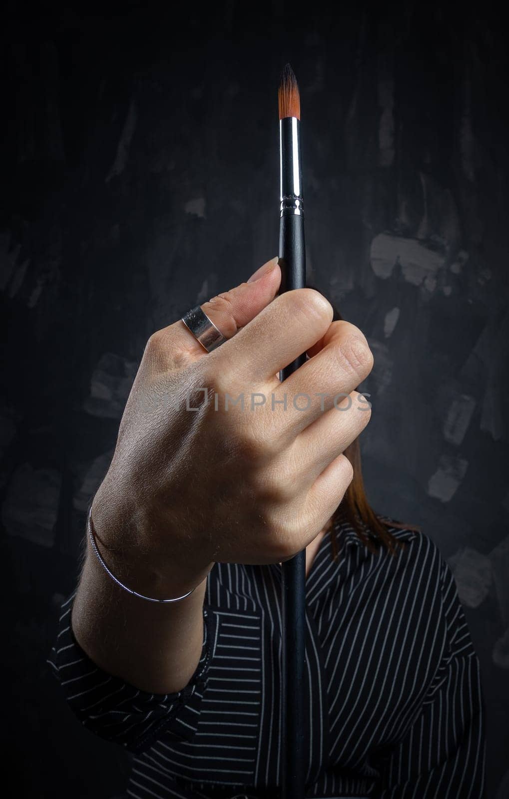 Portrait of a female artist, with brushes in her hands.
 Photo shoot on a black background in the studio