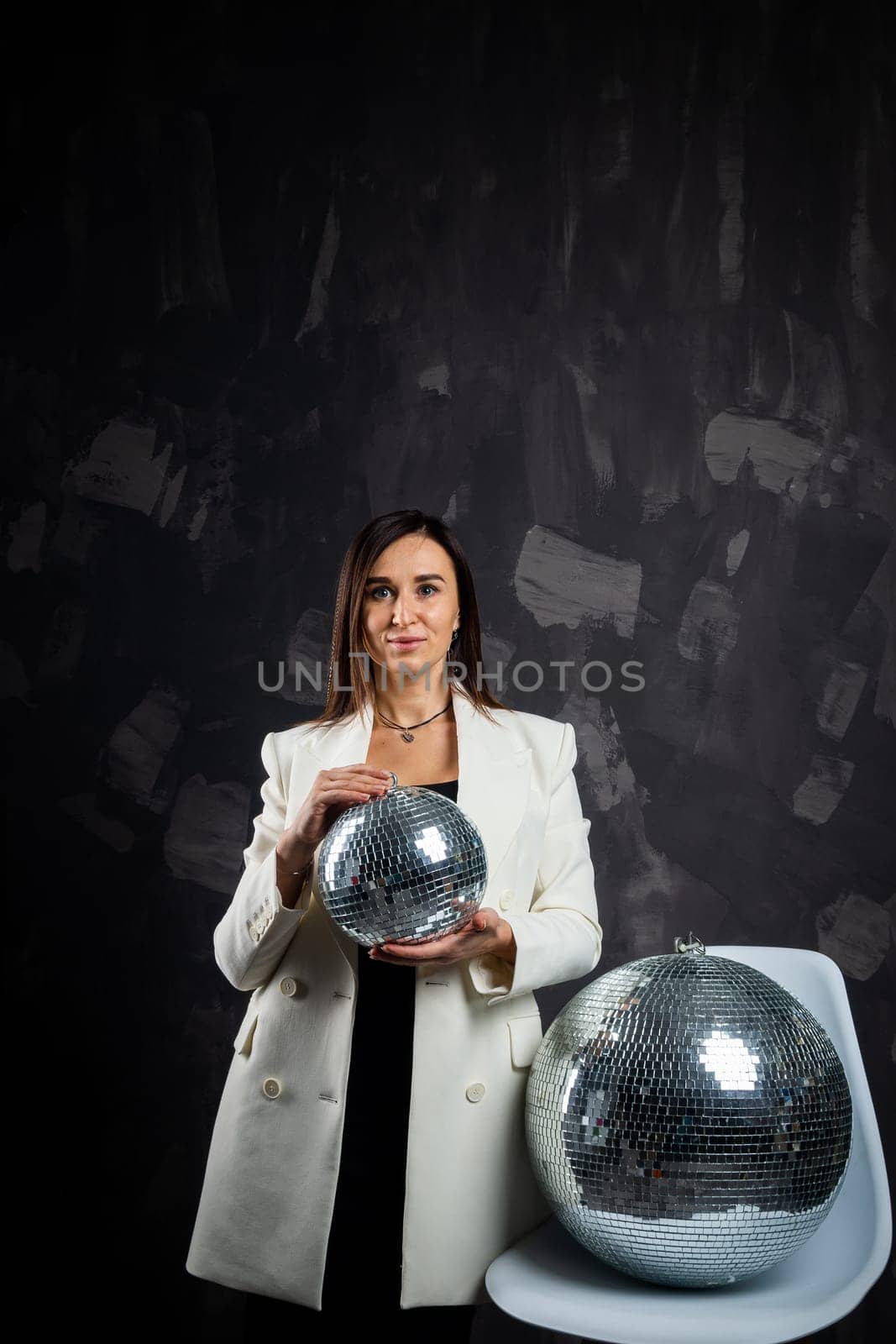 Portrait of a woman holding a silver disco ball. Taken in a photo studio. The concept of the party.