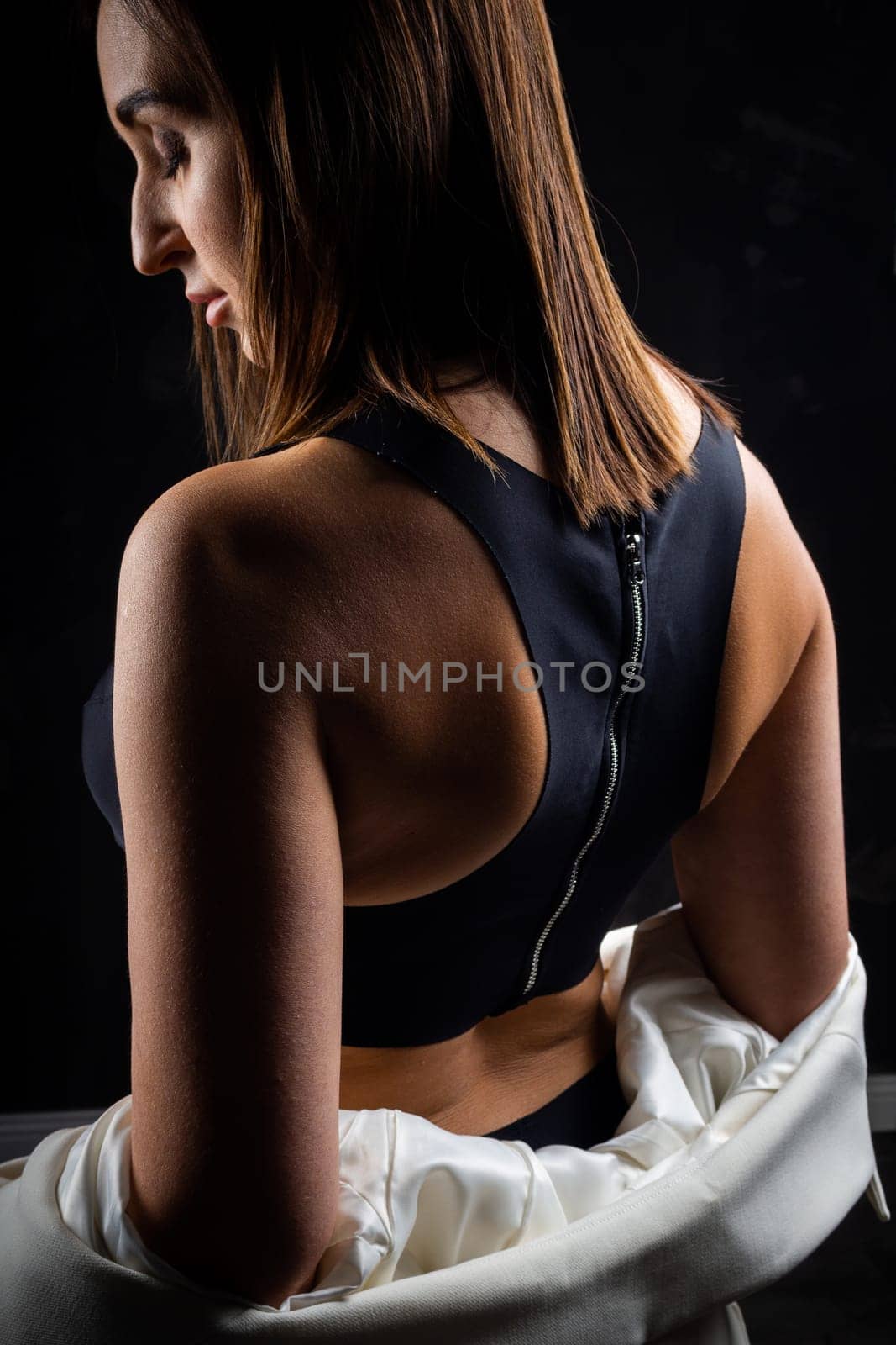 A business woman showing off her body in her underwear. Shot in the studio on a dark background.