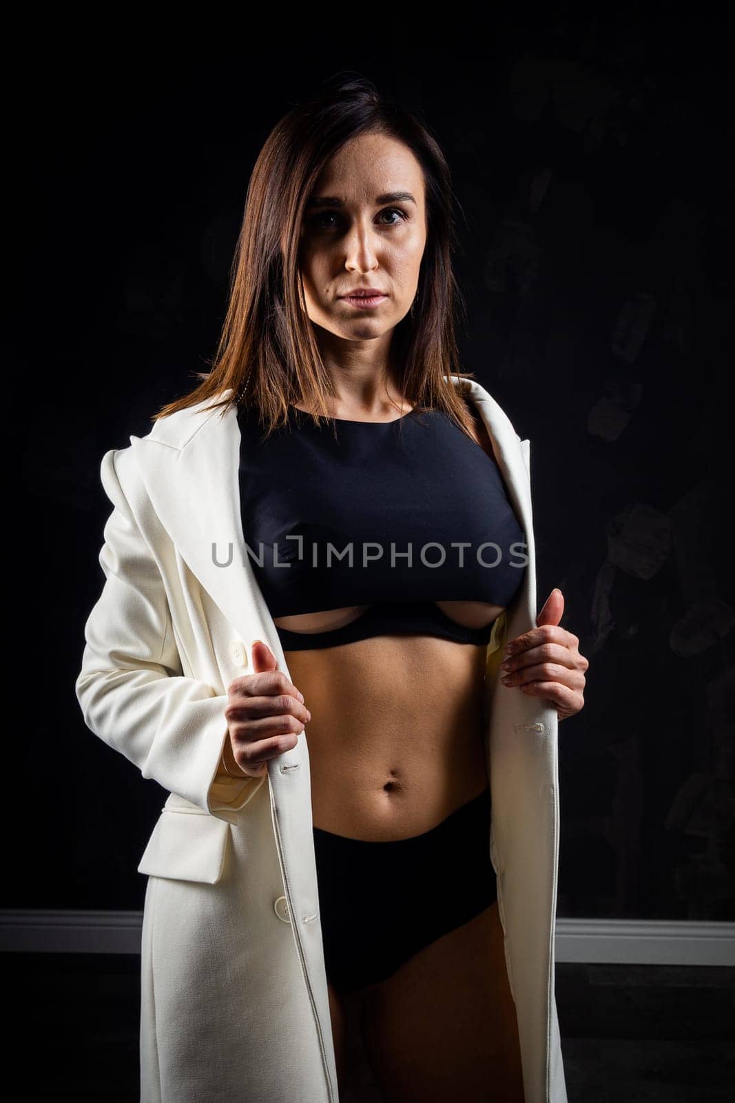 A business woman showing off her body in her underwear. Shot in the studio on a dark background.