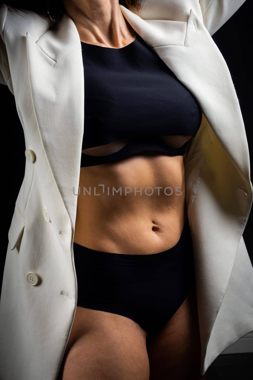 A business woman showing off her body in her underwear. Shot in the studio on a dark background.