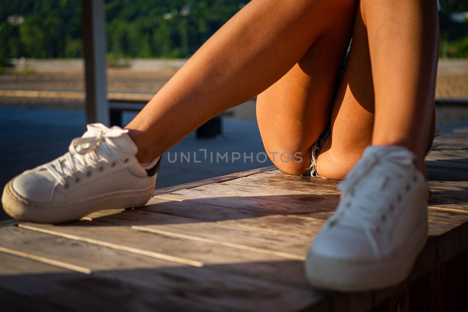 Portrait of an adult girl in summer shorts. Summer, sunny day on the beach.