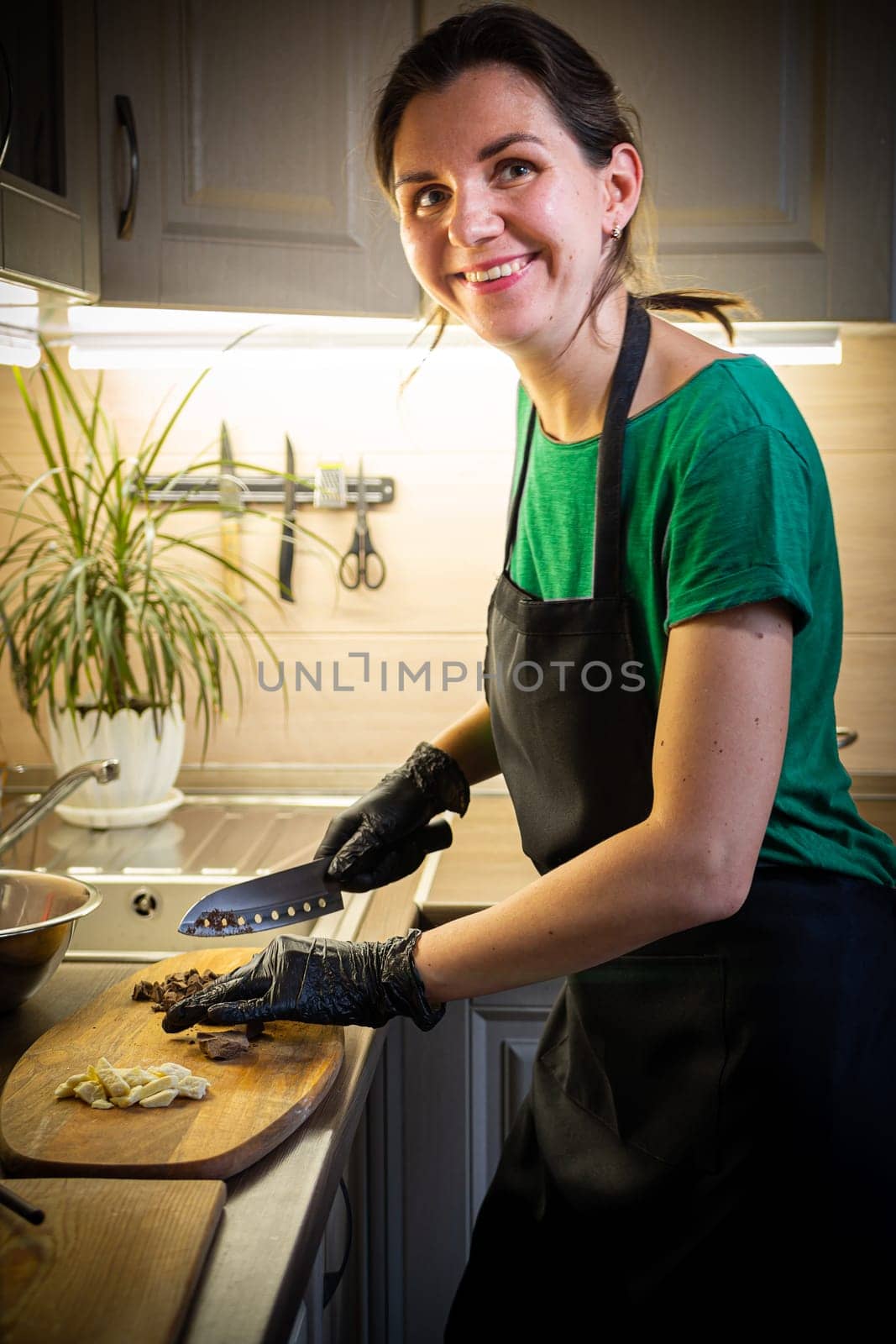 Woman cooking tasty melted chocolate on table in kitchen. Delicious dessert made of homemade chocolate.