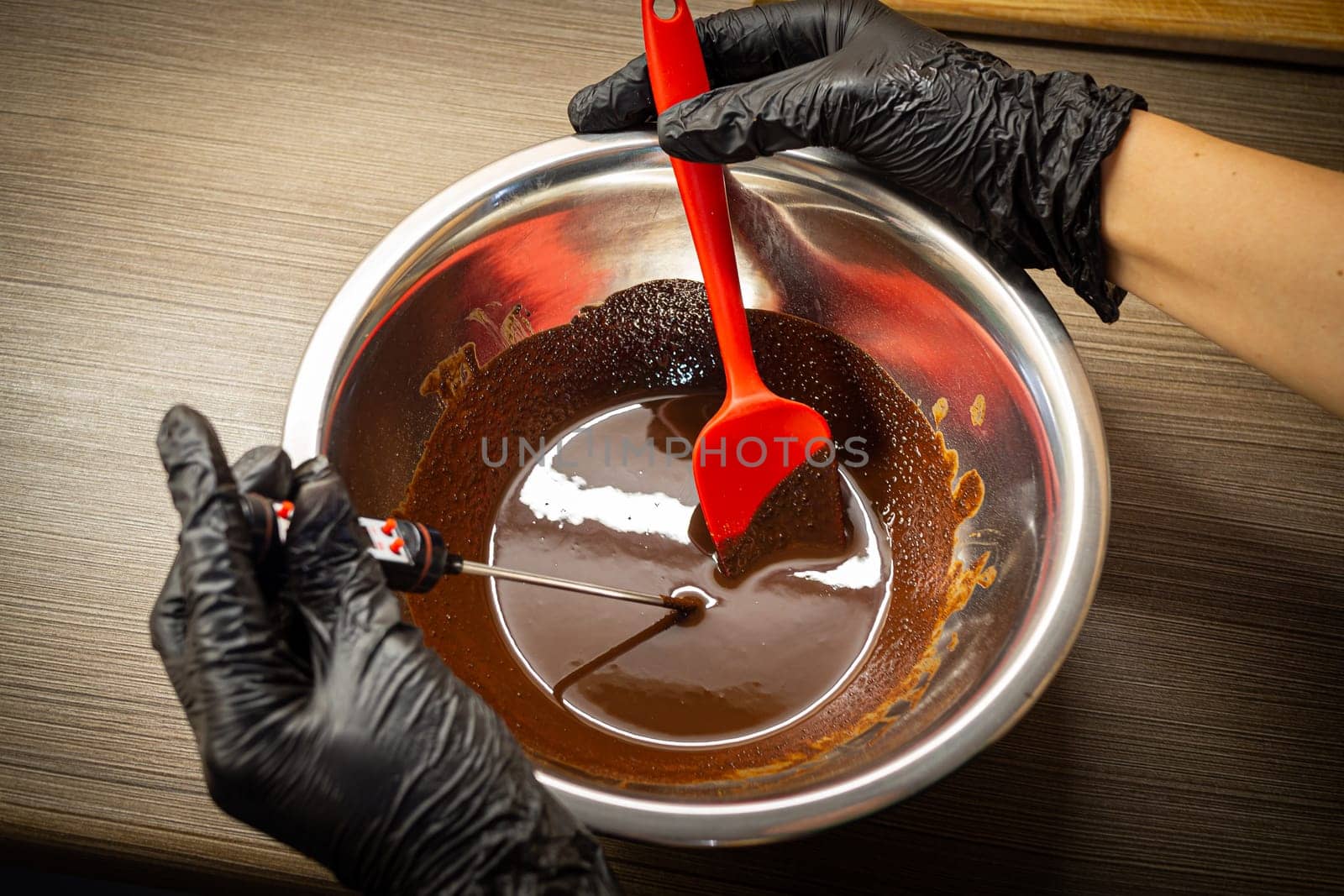 Woman cooking tasty melted chocolate on table in kitchen. Delicious dessert made of homemade chocolate.