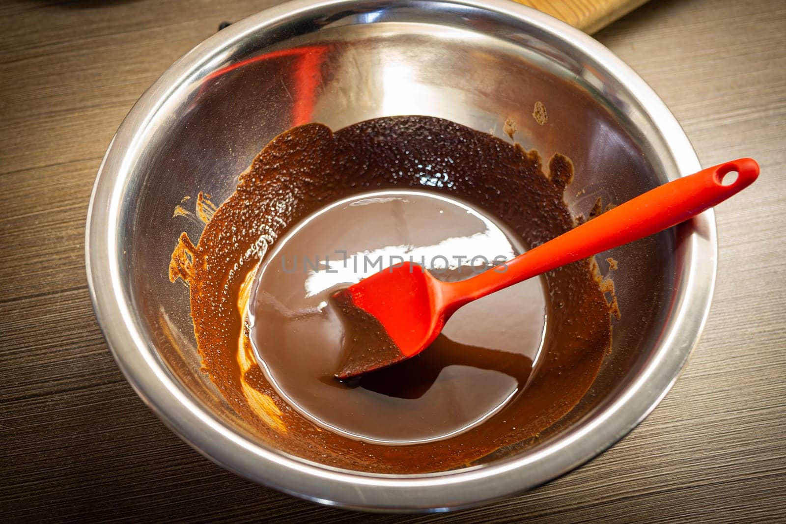 Woman cooking tasty melted chocolate on table in kitchen. by Evgenii_Leontev