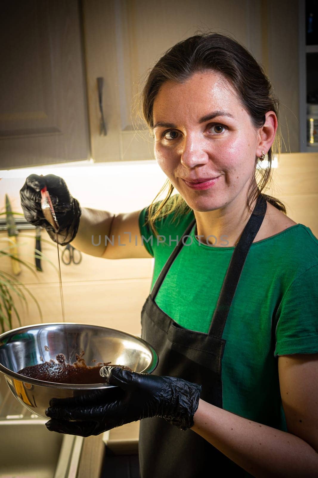 Woman cooking tasty melted chocolate on table in kitchen. Delicious dessert made of homemade chocolate.