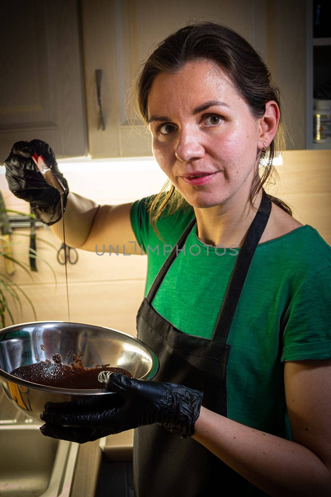 Woman cooking tasty melted chocolate on table in kitchen. Delicious dessert made of homemade chocolate.