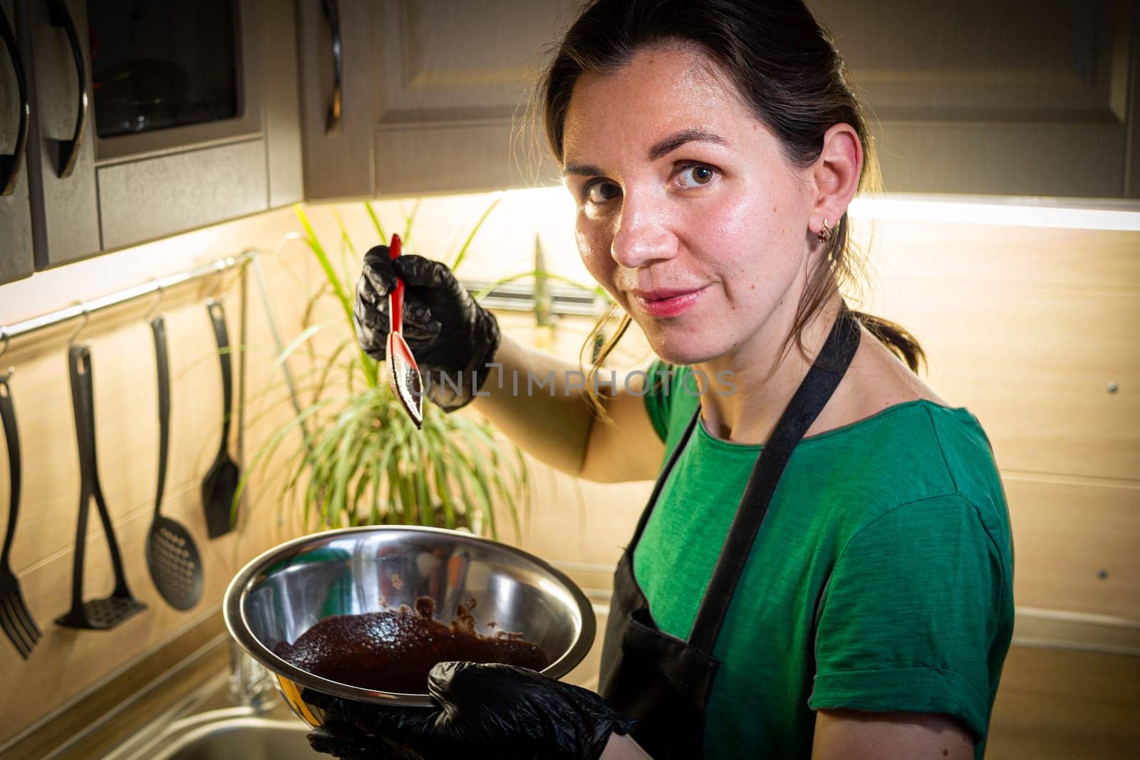 Woman cooking tasty melted chocolate on table in kitchen. by Evgenii_Leontev