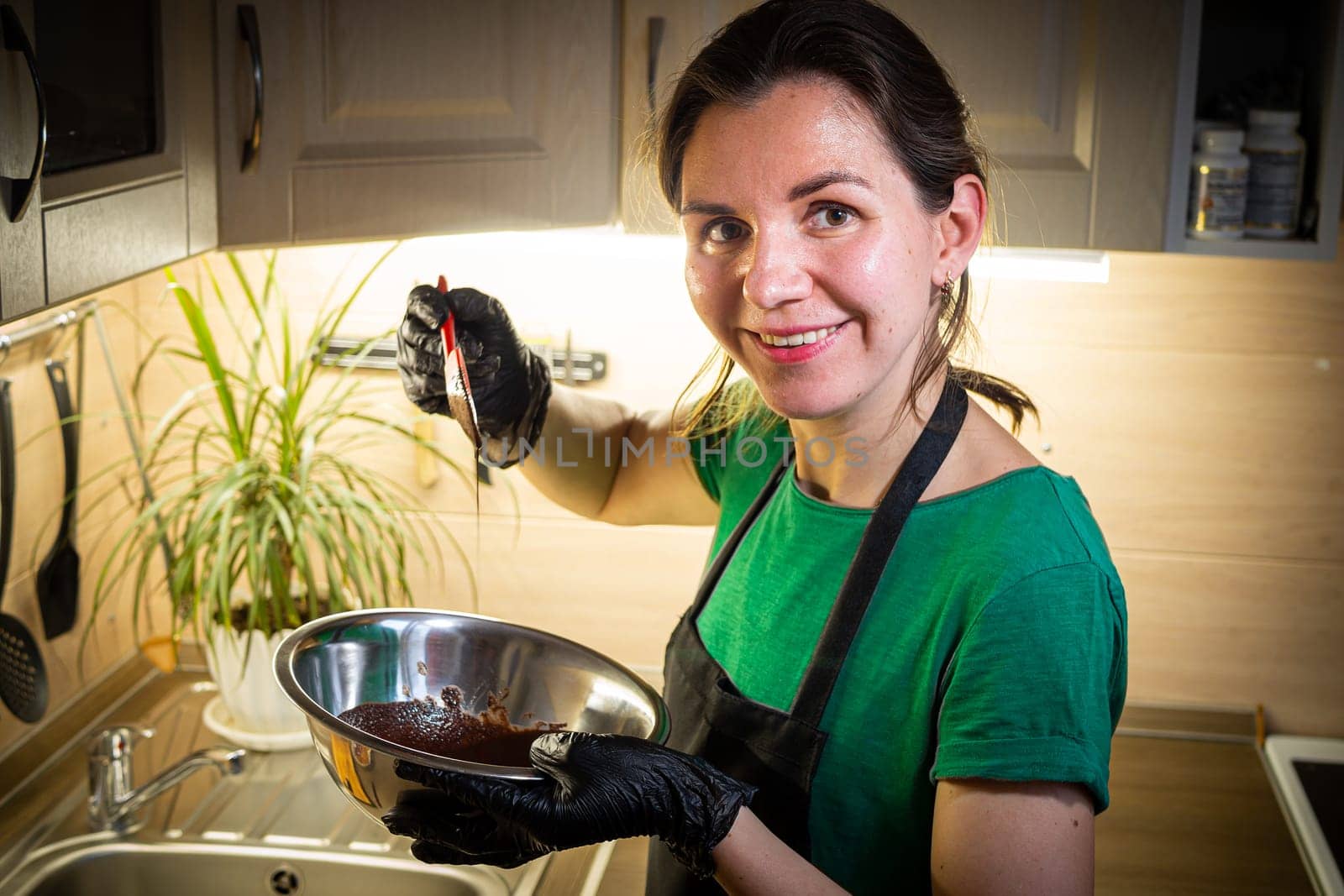 Woman cooking tasty melted chocolate on table in kitchen. Delicious dessert made of homemade chocolate.