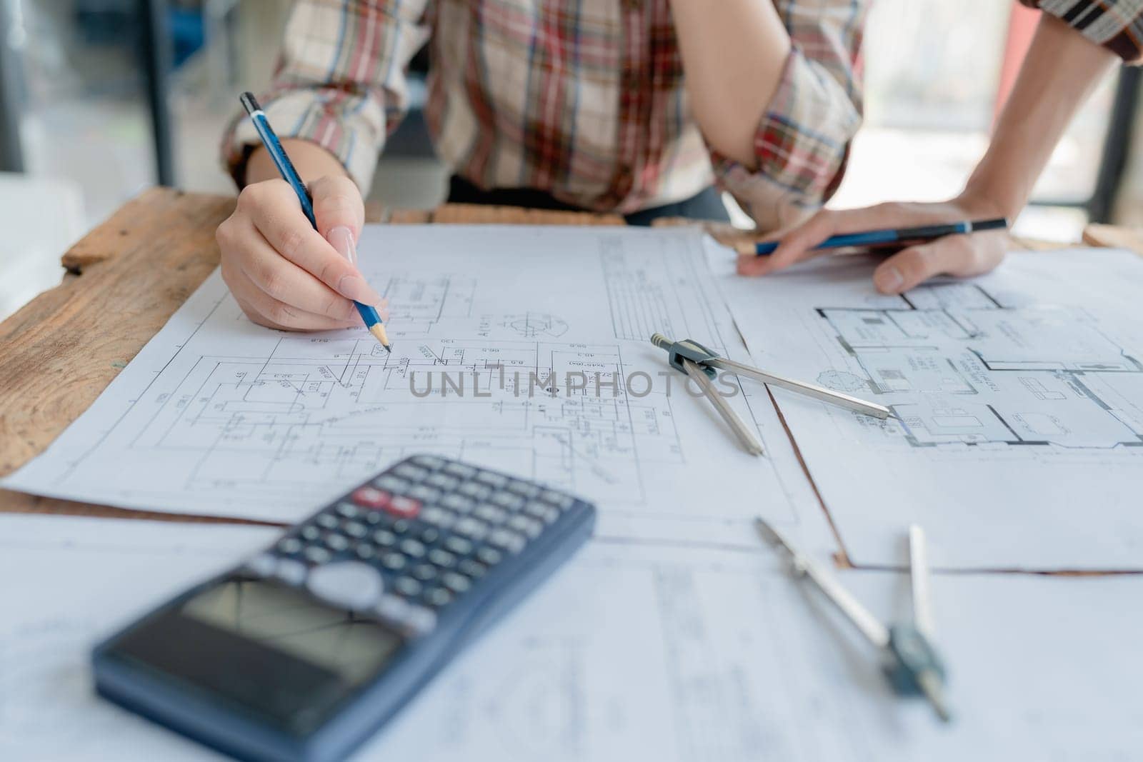 multi ethnic engineer brainstorming and measuring for cost estimating on blueprint and floor plan drawings about design architectural and engineering for houses and buildings by Manastrong