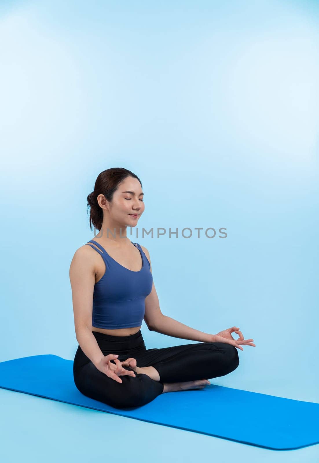 Asian woman in sportswear doing yoga exercise on fitness mat. Vigorous by biancoblue