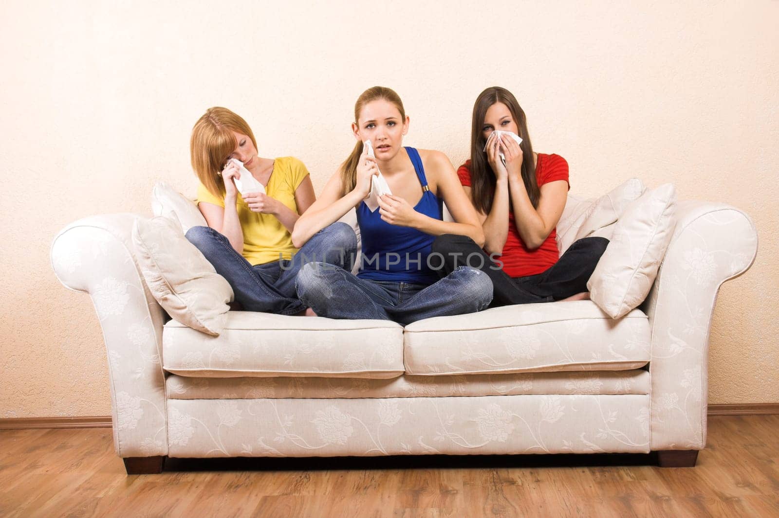 Three crying women on a sofa