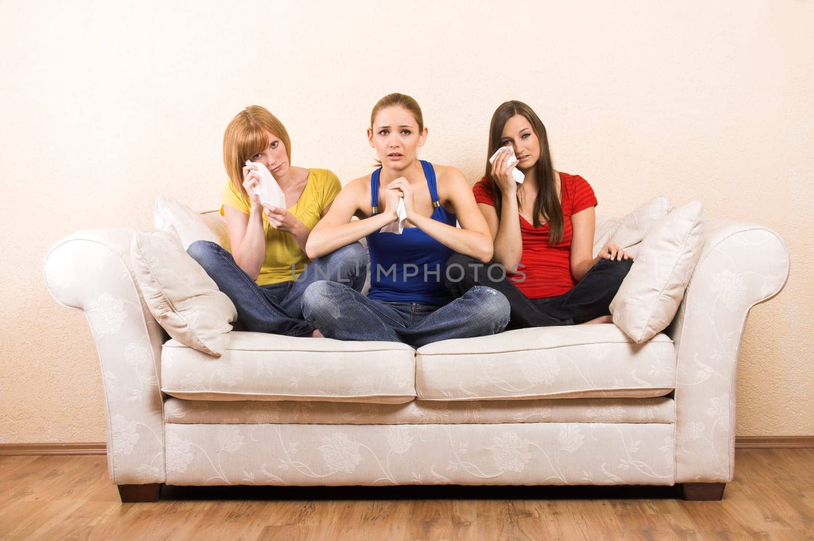 Three crying women on a sofa