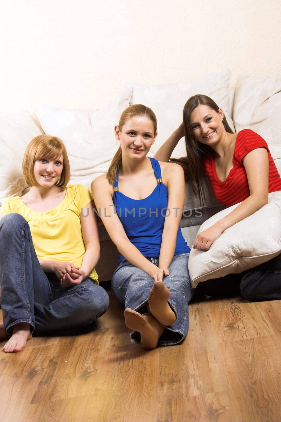 Three laughing women in front of a sofa