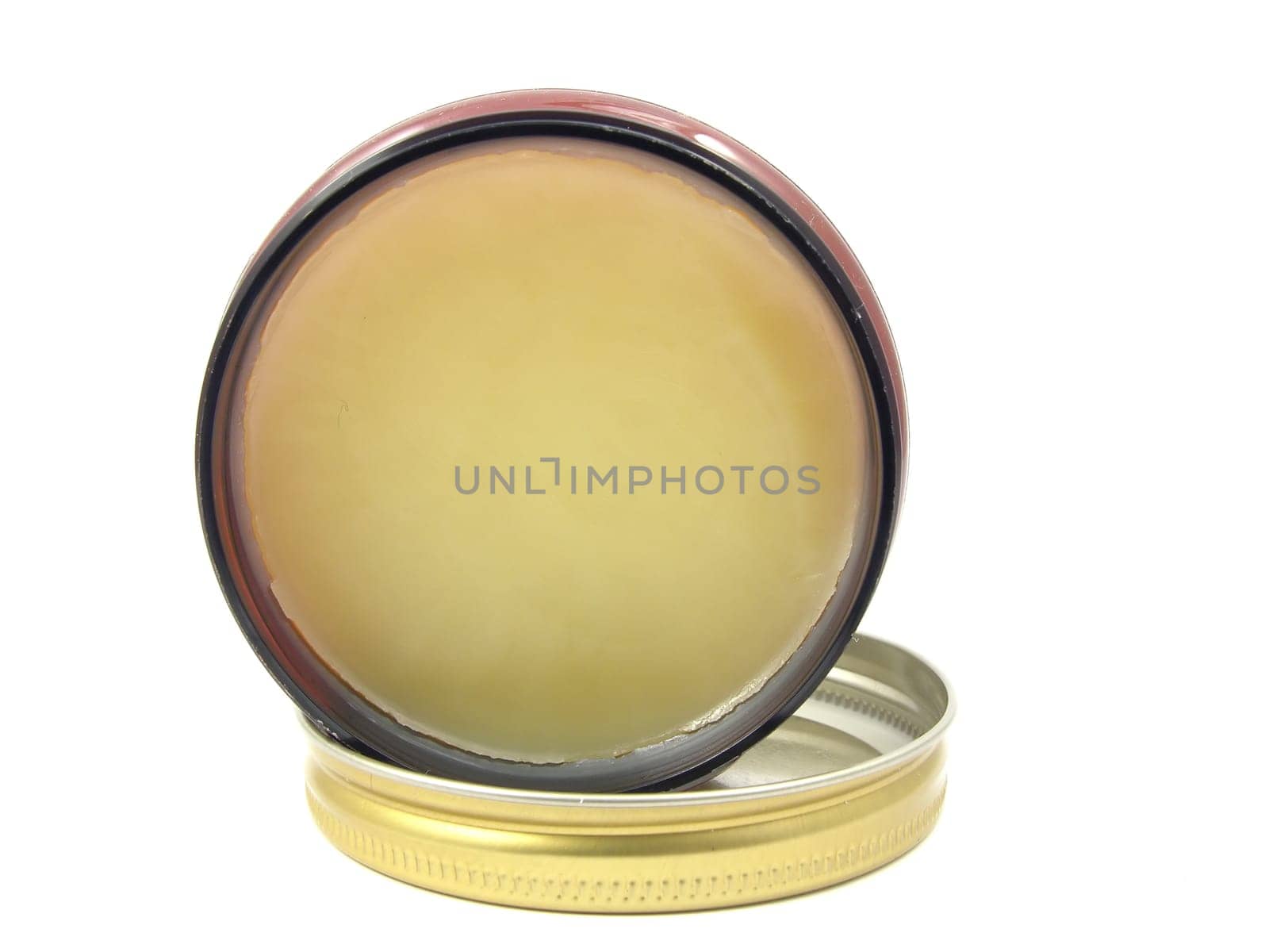 Yellow hair wax in an open jar with lid