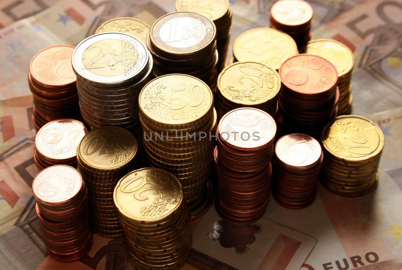 Stack of euro coins on 50 euro banknotes