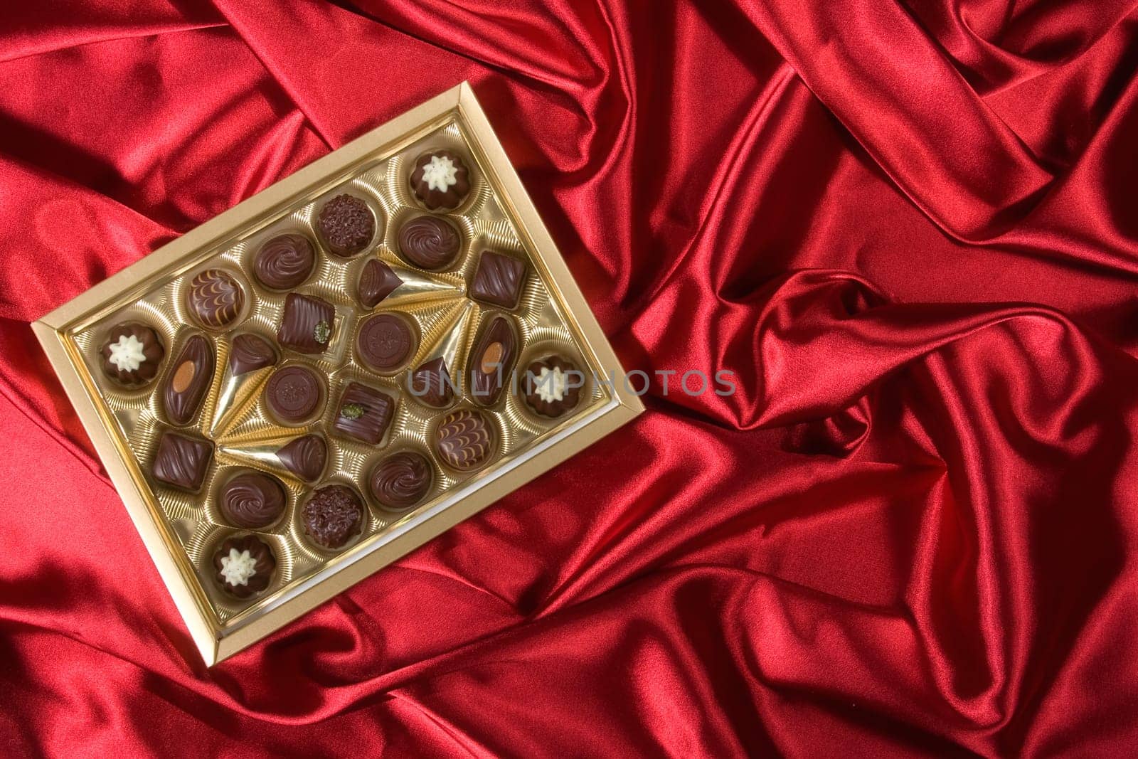 Golden chocolates box on red satin