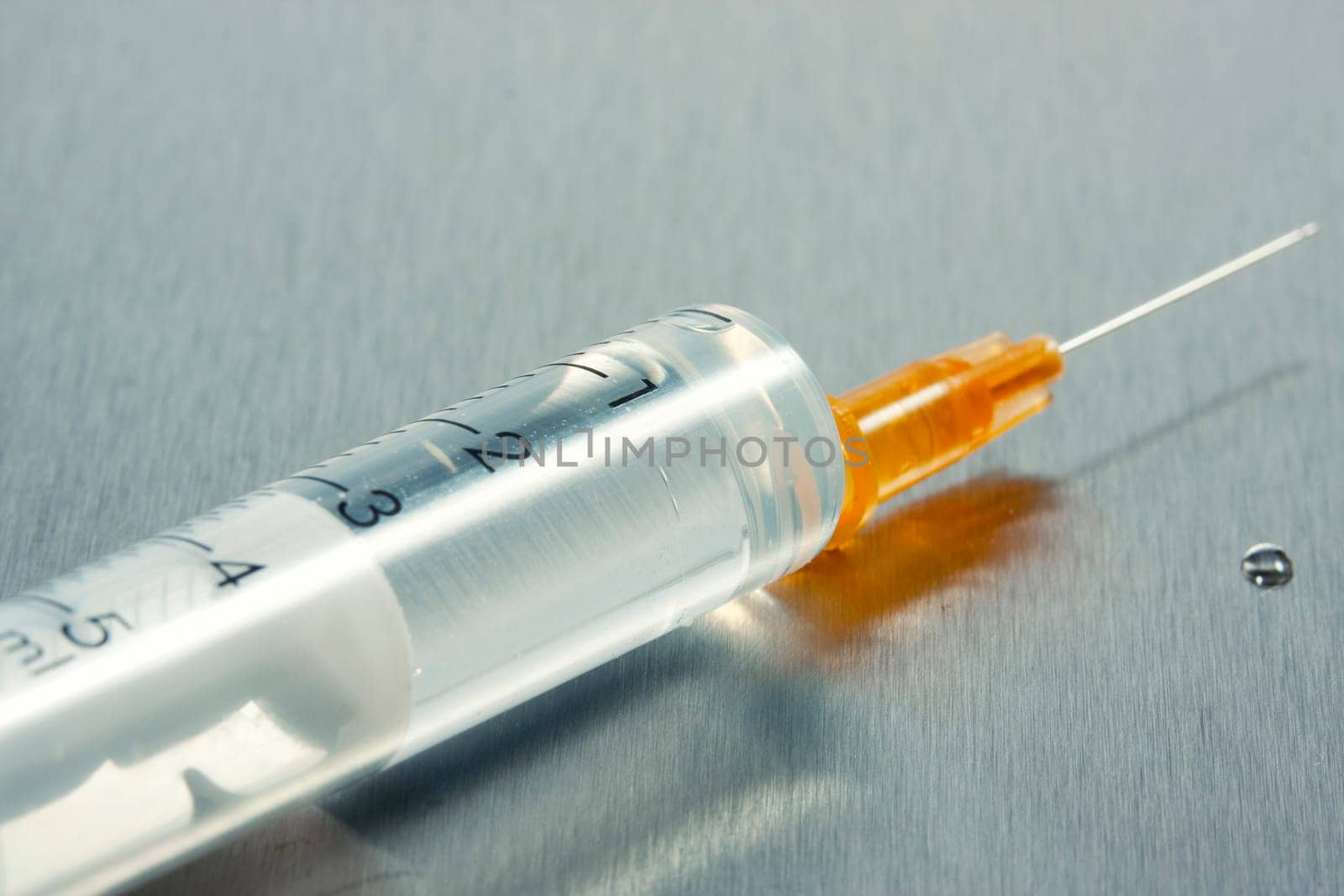 Drop of a liquid on a needle of syringe