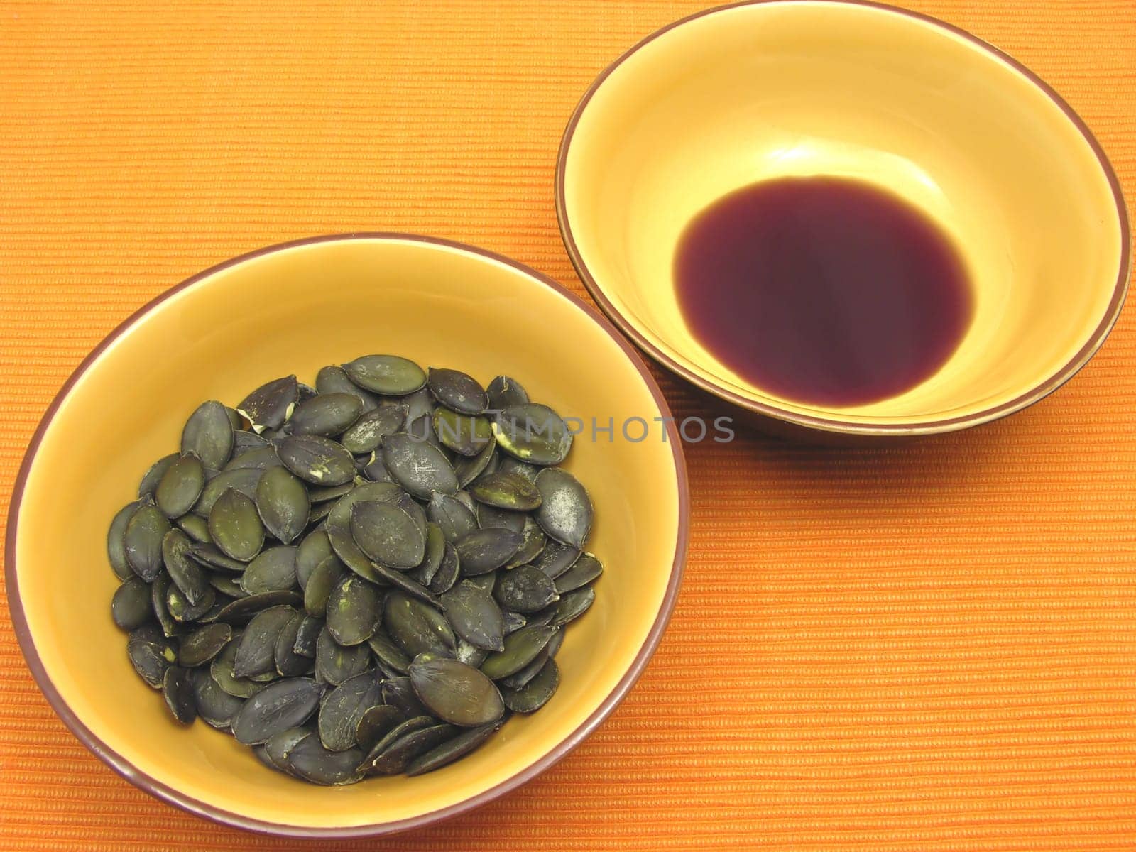 Two ceramic bowls with pumpkin seeds and pumpkin seed oil