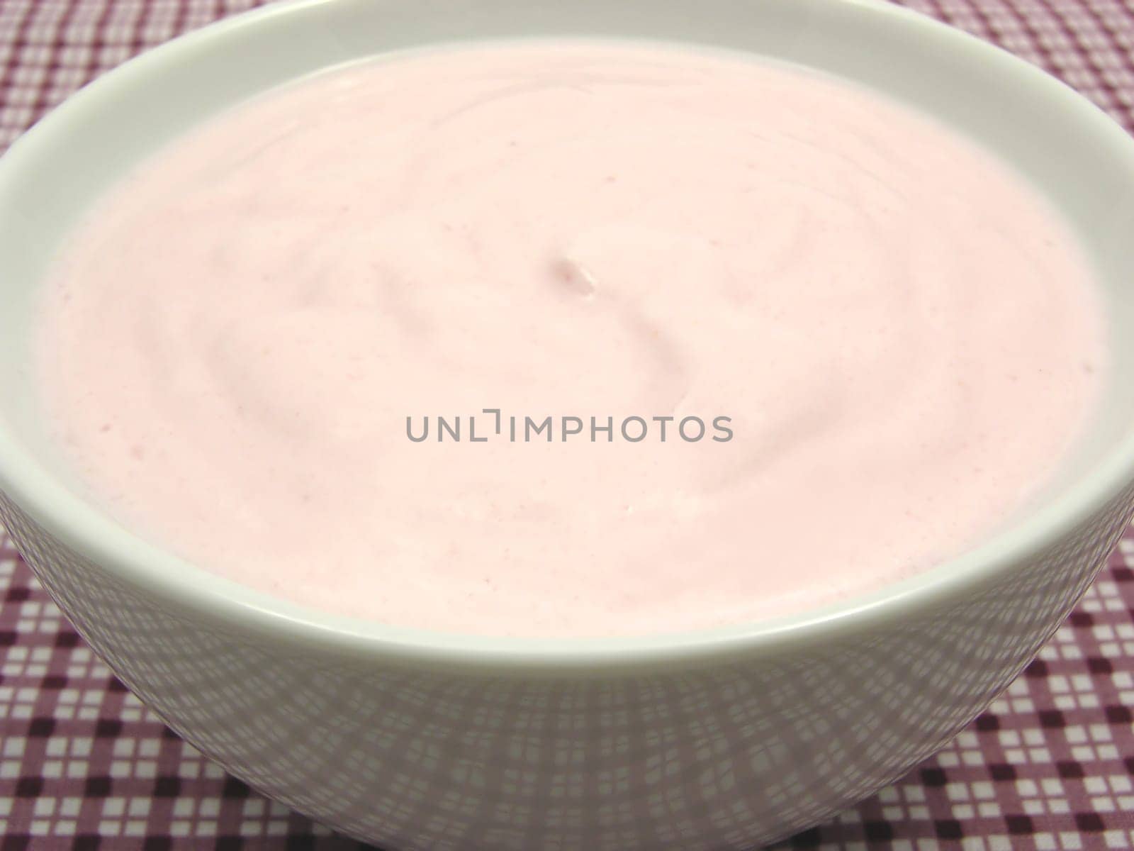 Strawberry curd in porcelain bowl on checkered cloth