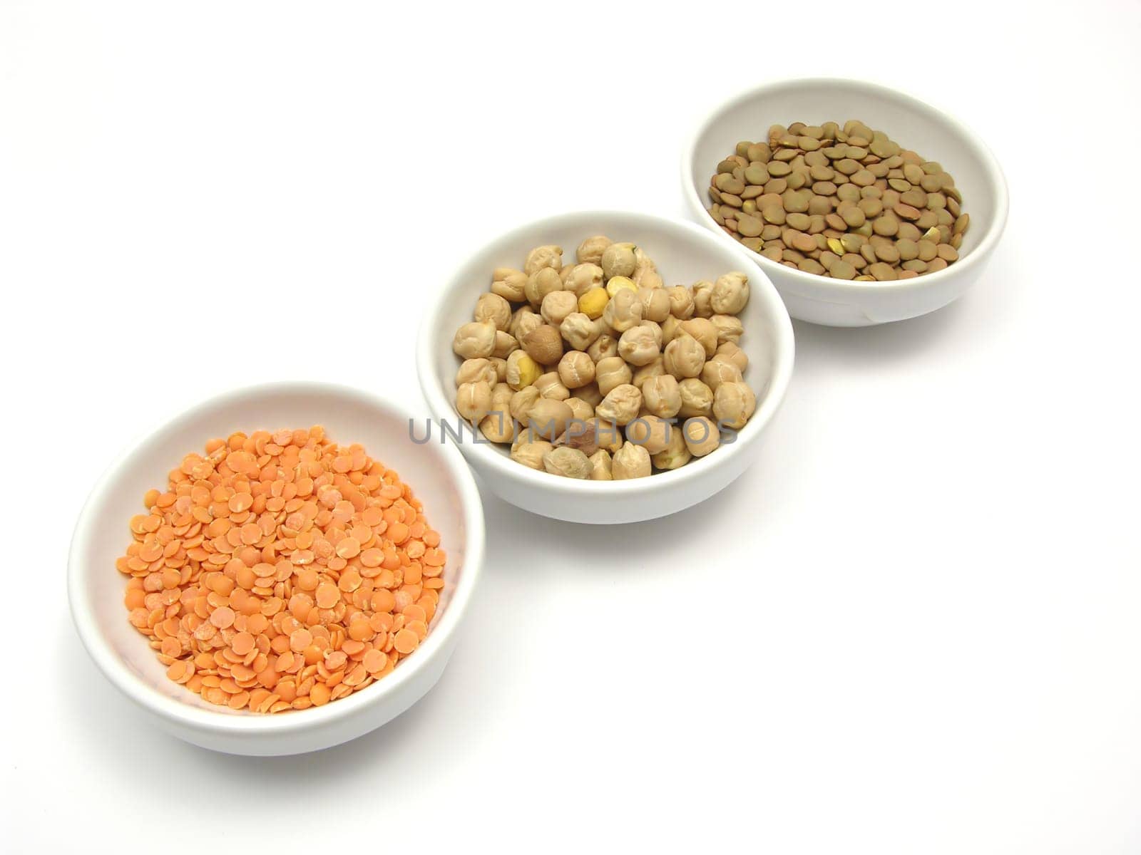 Three porcelain bowls with chickpeas,red and plate lentils