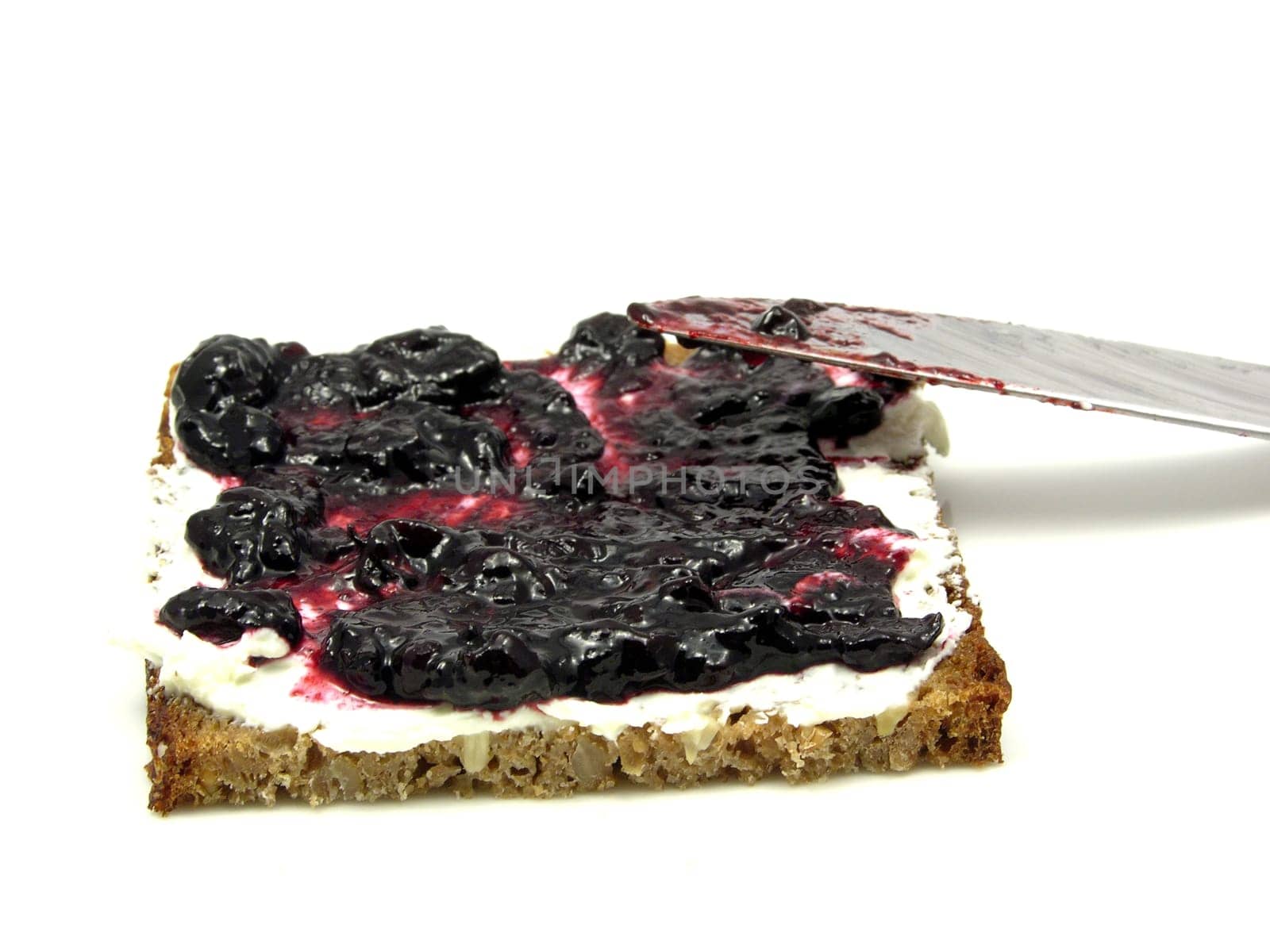 Bread with butter and blueberry jam on plate with knife
