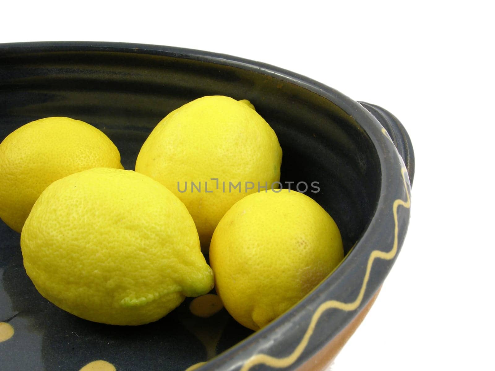 Four lemons in a ceramic bowl