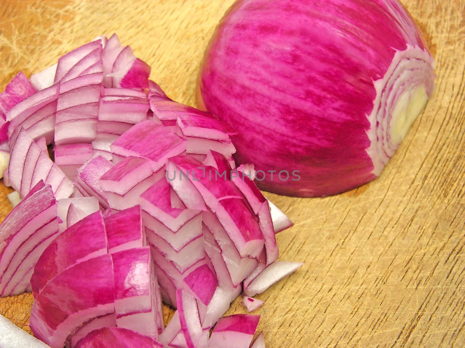 Red onion cut into cubes on wooden board