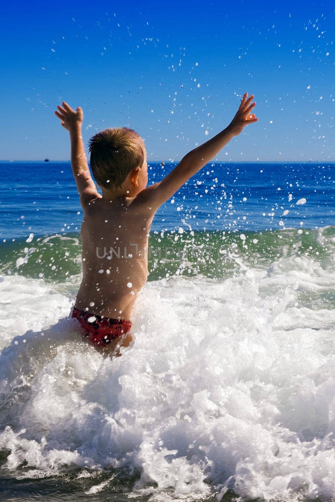 young child playing in the waves
