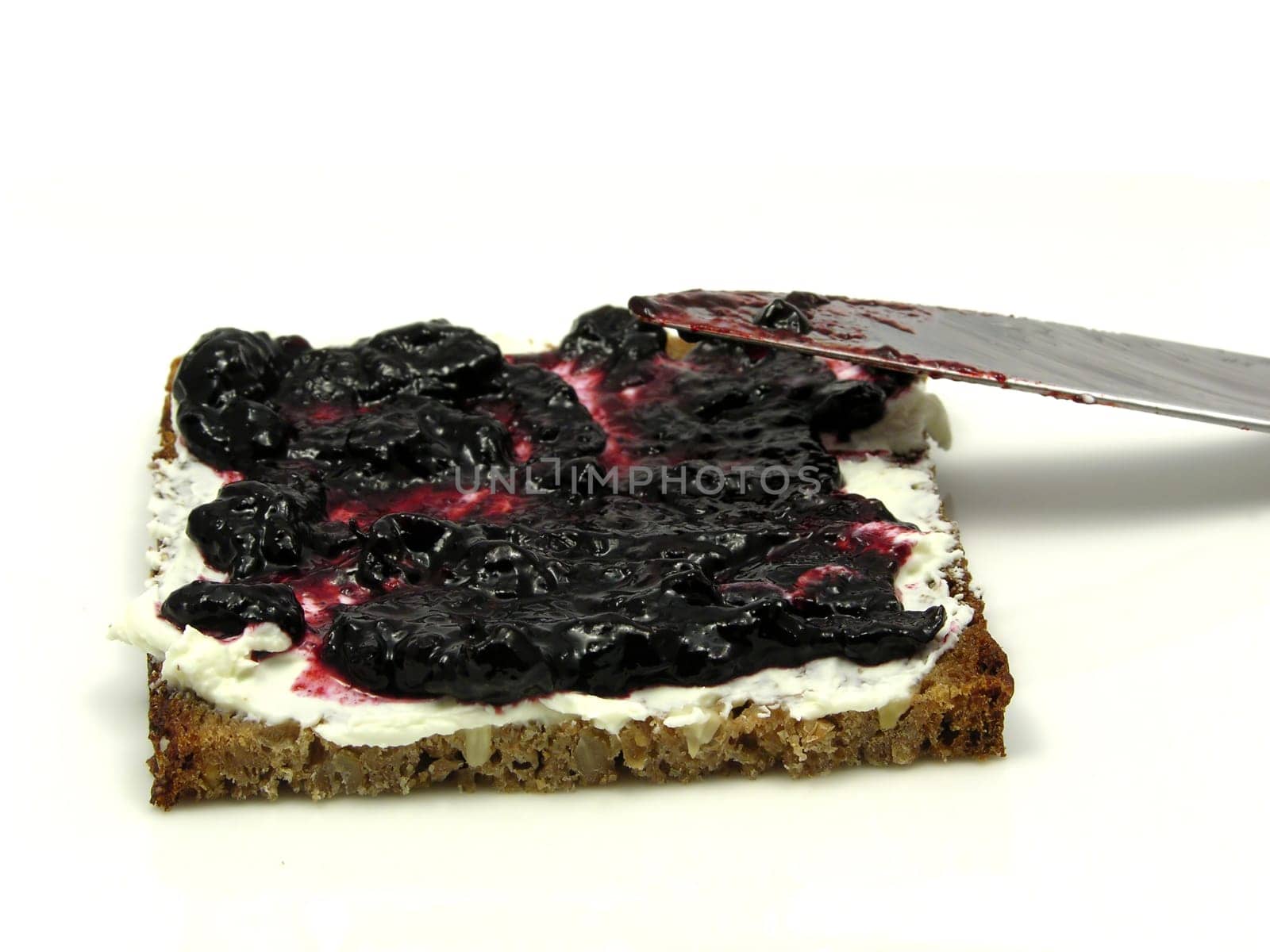 Bread with butter and blueberry jam on plate with knife