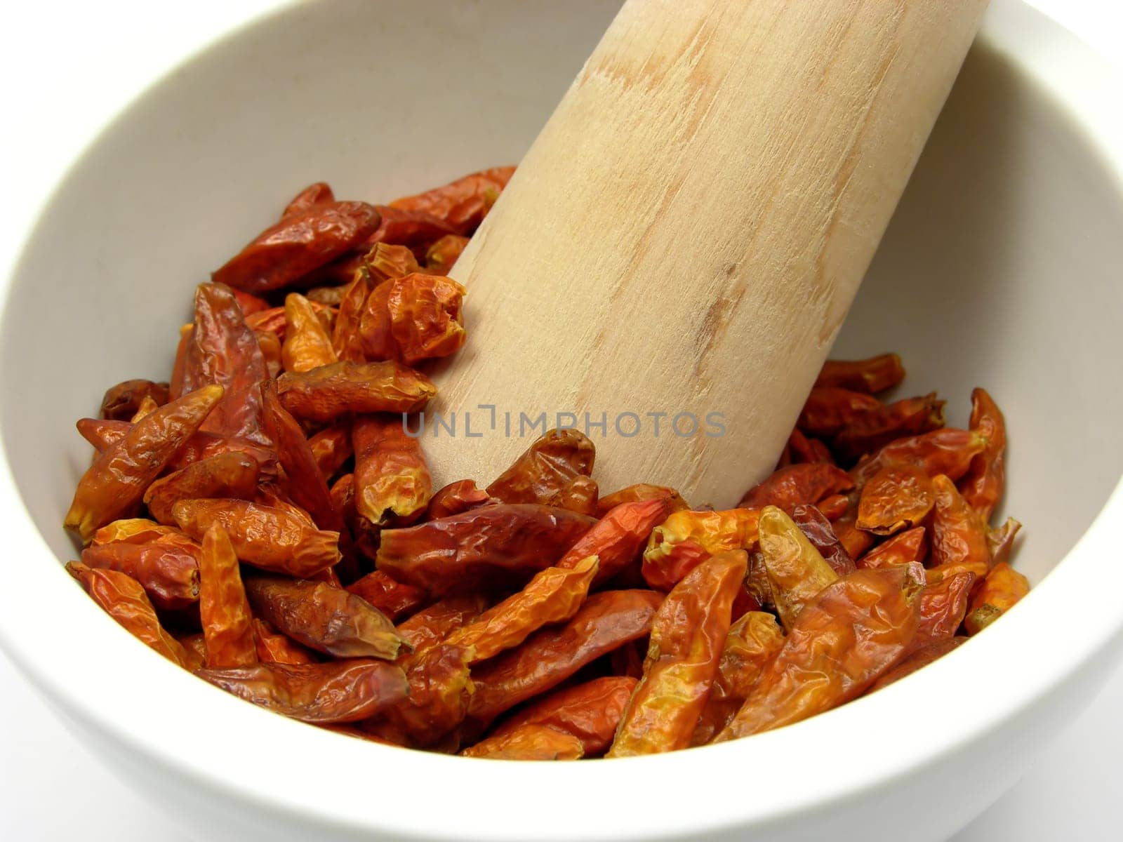Dried red chili peppers in porcelain bowl with mortar