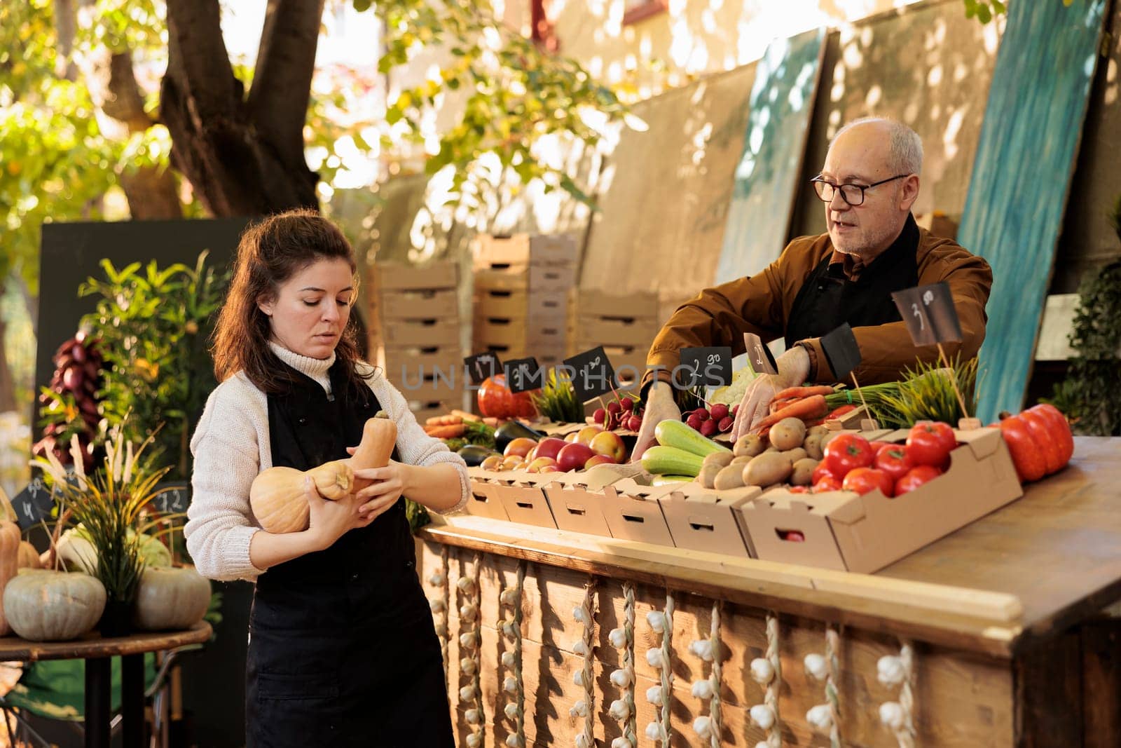 Local stand vendors starting the day with fresh natural produce, working at marketplace stall to sell healthy products. Young woman putting fruits and vegetables on farmers market.
