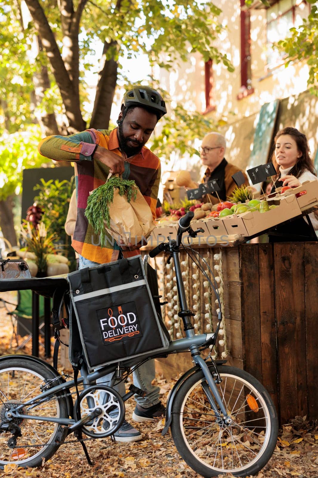 Male food delivery courier picking up order of fresh homegrown organic produce, working with small business owner. Farmers and merchants going online to sell healthy natural bio farm food.