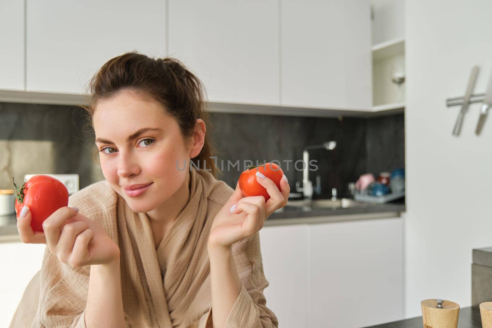 Portrait of beautiful woman cooking in the kitchen, chopping vegetables on board, holding tomatoes, lead healthy lifestyle with preparing fresh salads, vegan meals by Benzoix