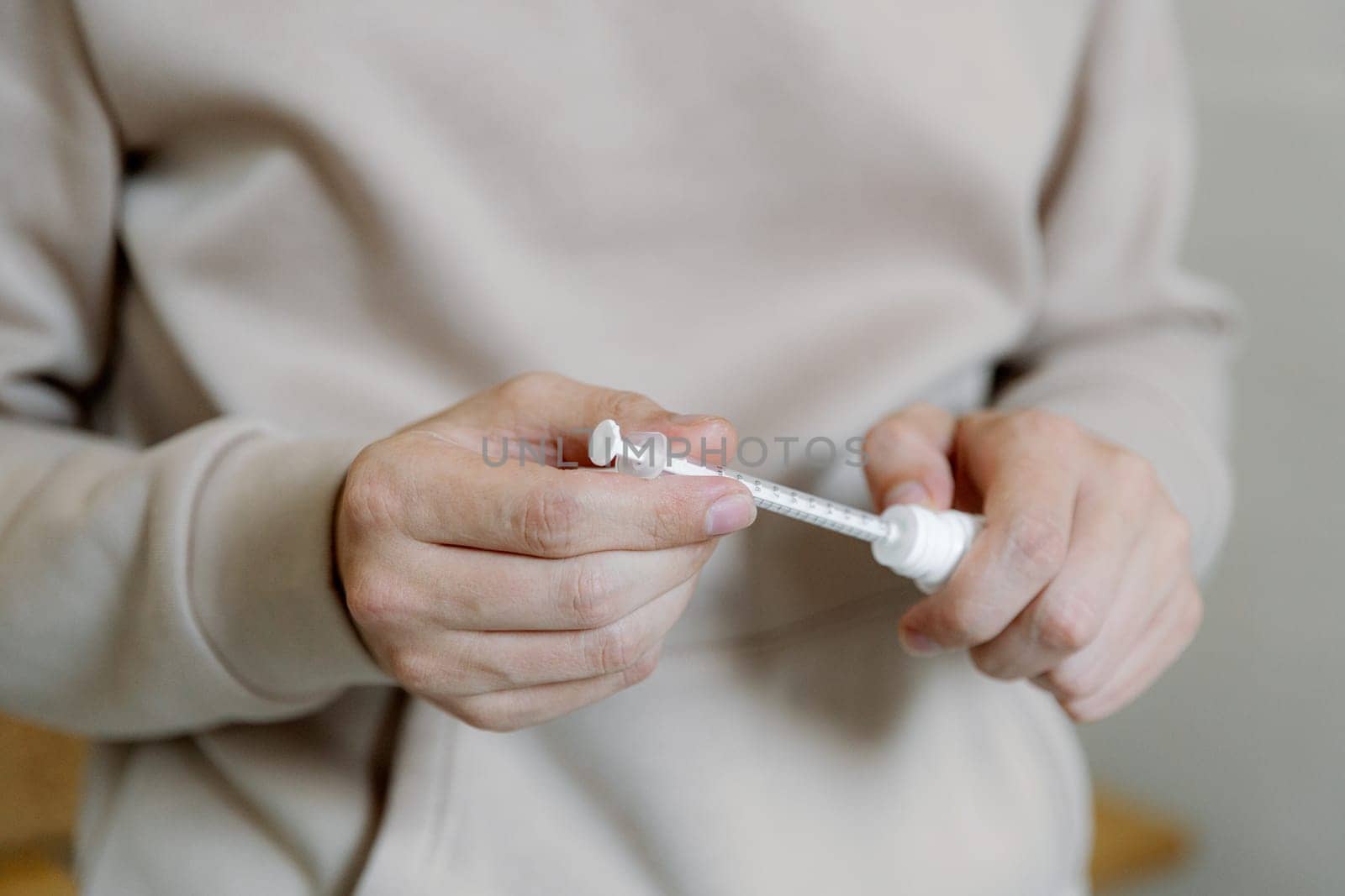 One young Caucasian unrecognizable man draws medicine from a bottle with a syringe to treat a cat, side view close-up.