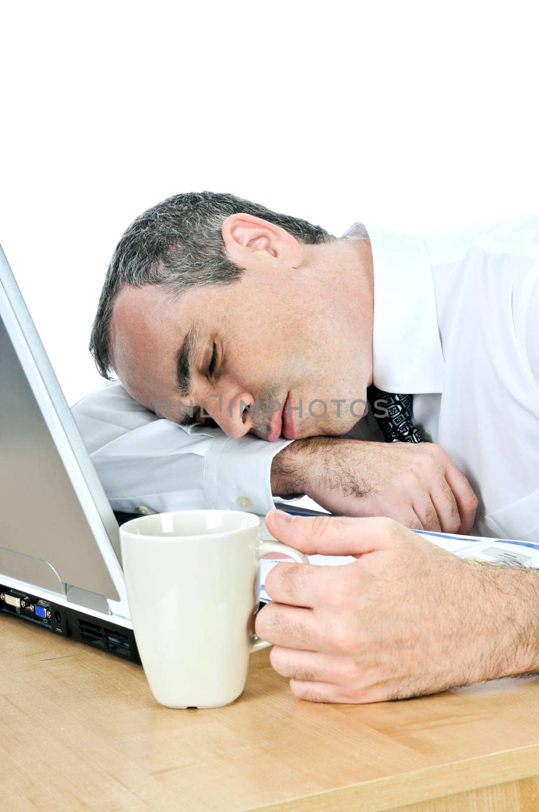 Businessman asleep at his desk on white background
