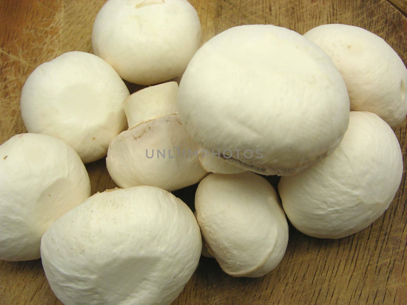 White cleaned mushrooms on wooden plate