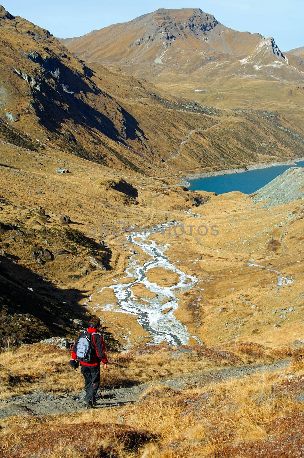 Hikers descending over an alpine pasture into the valley to a mountain lake,Valais Alps,Sch