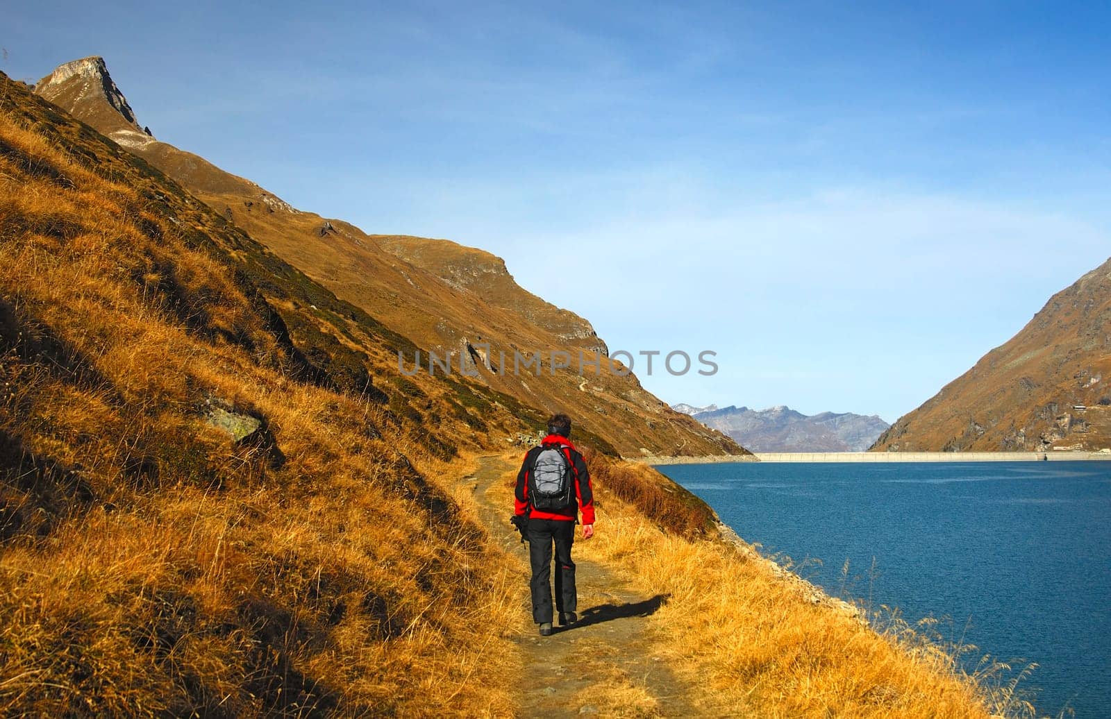 Hiker on an autumn hike on the banks of a dam in the mountains