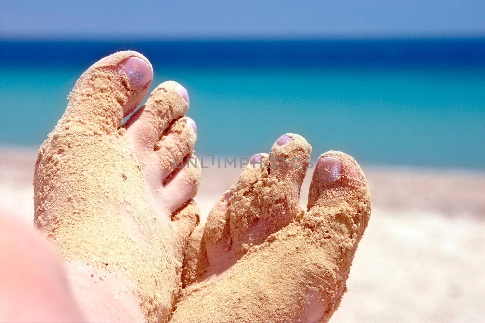 women feet with sands at the seaside