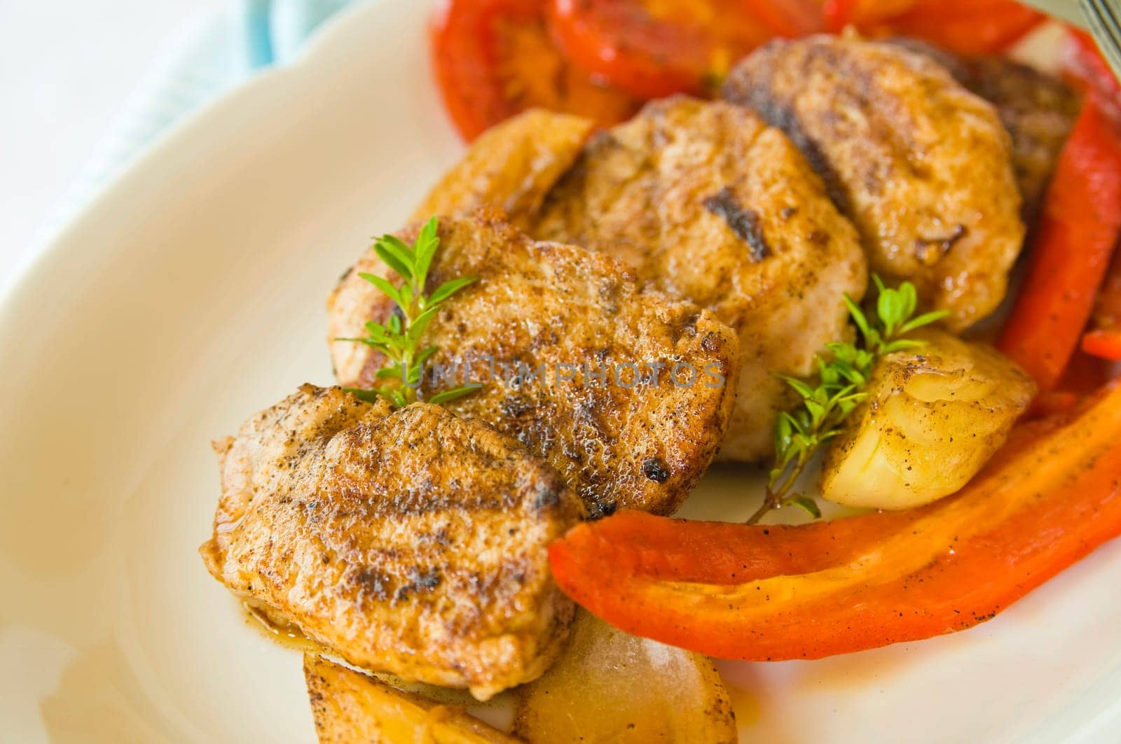Pork medallions with fried onions,bell pepper and tomatoes on plate anger