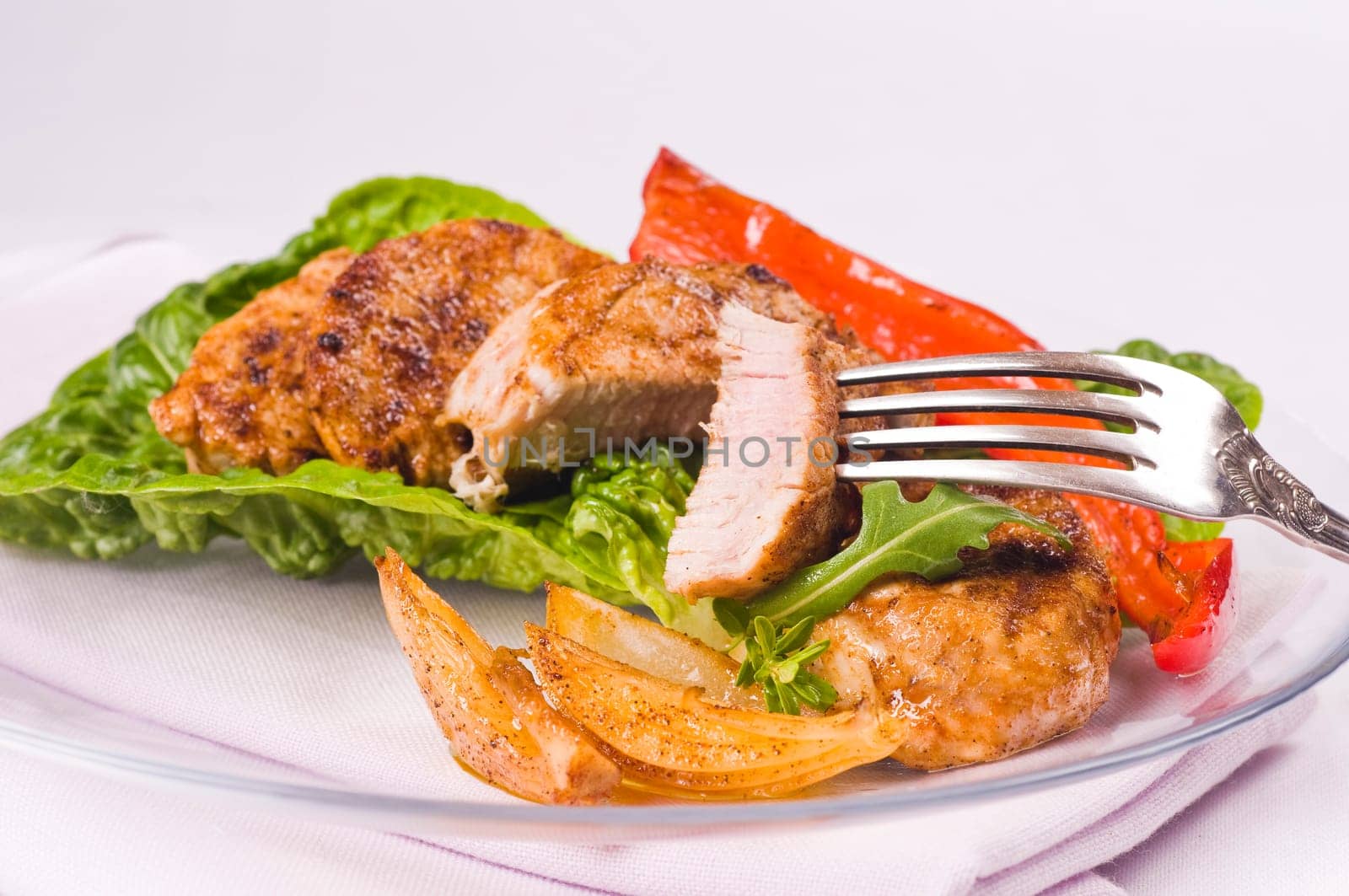 Pork medallions with fried onions,bell pepper and tomatoes on plate anger