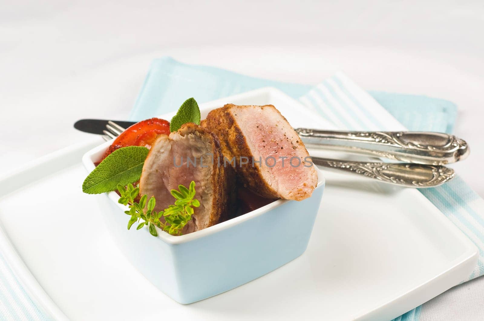 Pork tenderloin,fried in light blue bowl with herbs