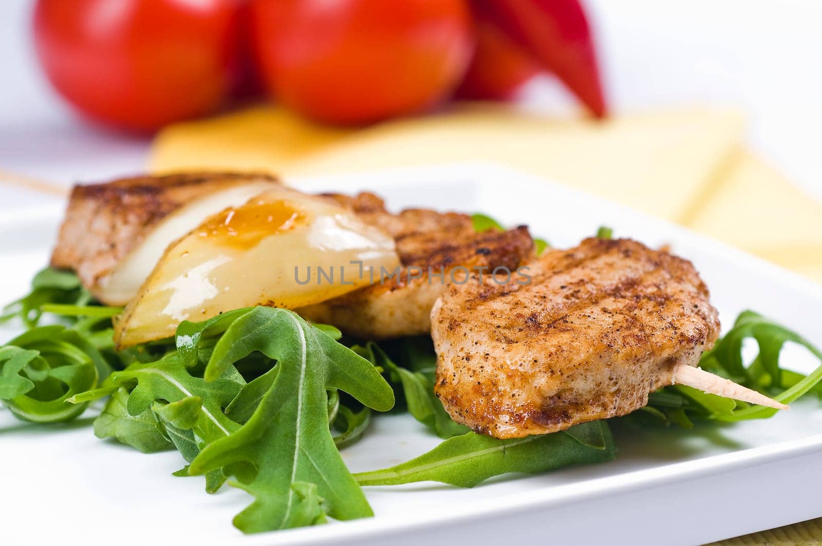 Pork medallions on a skewer with onions on rocket salad